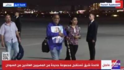 مواطن عائد من السودان يحمل صورة الرئيس السيسي لدى وصوله مطار قاعدة شرق